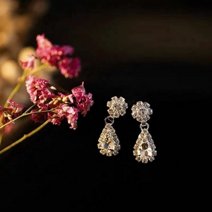 Detailed view of silver crystal drop earrings with pear-cut rhinestone and floral accents