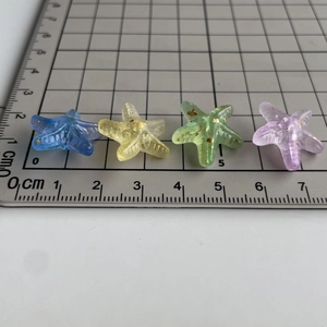Close-up of 2cm colorful gradient acrylic starfish beads with glitter on a size ruler