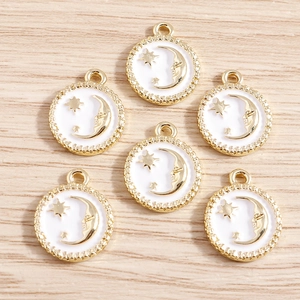 Detail of 6 gold alloy pendants featuring white enamel celestial moon and star patterns