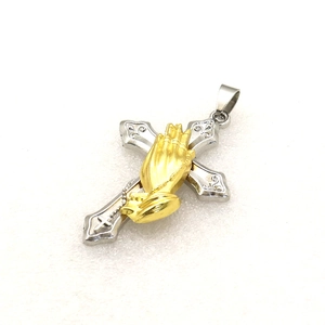 Detailed view of two-tone religious pendant with silver cross and golden praying hands