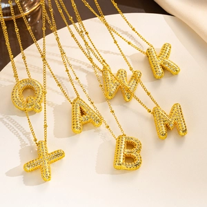 Close-up of gold-plated alphabet pendants with zircon micro-pave on a round base