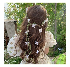 Detailed back view of white floral crown wreath with long green leaves and vine tassels