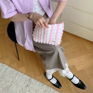 Detail of pink and white checkered plush makeup bag with soft fabric texture