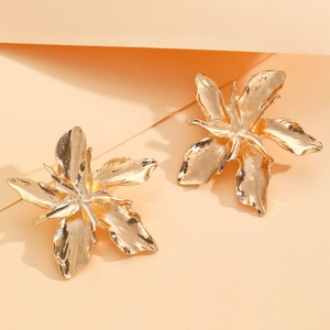 Exquisite golden metallic 3D flower earrings with organic petal textures on orange backdrop