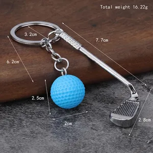 Minimalist golf keychain with silver metal club and blue ball on rustic wooden surface