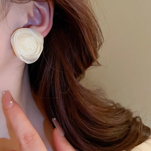 Close-up of elegant cream white mesh flower stud earrings worn by a female model