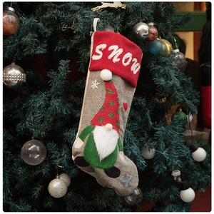 Detail of Christmas stocking featuring a knitted gnome and white SNOW embroidery on a tree
