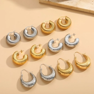 Close-up of assorted hammered and ribbed titanium steel hoop earrings in gold and silver