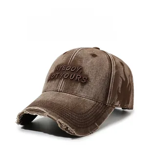 Close-up of distressed washed brown baseball cap with embroidered letters and frayed brim