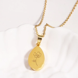 Gros plan d'un pendentif goutte d'or avec motif floral gravé sur un plateau en coquillage