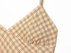 Close-up of orange plaid seersucker fabric texture and thin strap of the dress