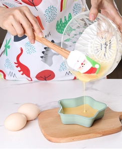 Action shot of Santa silicone spatula pouring batter from glass bowl into star mold