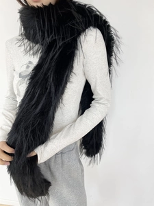 Detail showing the fluffy faux fur texture and long length of the black plush winter scarf