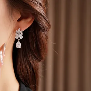Elegant silver wheat ear leaf earrings with pear drop zircon stones on a model