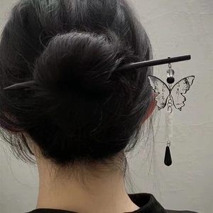 Detailed view of a Chinese wooden hair pin with butterfly pendant on model's bun