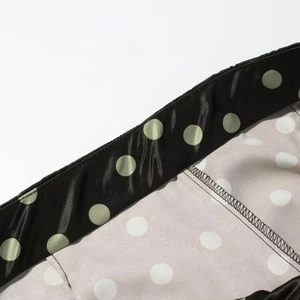 Detailaufnahme von schwarzem und cremefarbenem Polka-Dot-Satin mit feinen Nähten