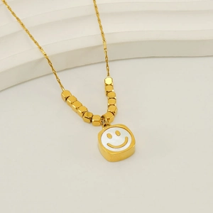 Detail of gold titanium steel necklace with square smile pendant and metal beads