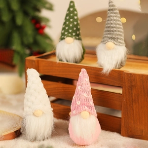 Detail of four colorful knitted Christmas gnomes on a rustic wooden crate with bokeh lights