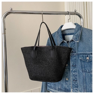 Detail of black woven straw tote bag with slim shoulder straps and purple lining texture
