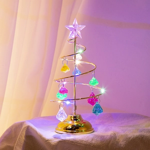 Detail of a golden spiral iron Christmas tree with colorful crystal ornaments and LED star