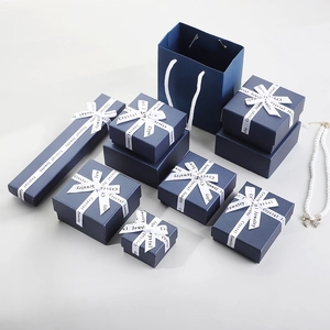 Navy blue jewelry gift box set with white ribbons and pearl necklace on white background