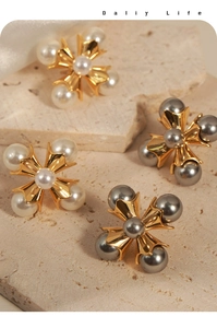 Detailed view of cross-shaped pearl earrings in gold setting on a stone display pedestal