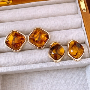 Macro shot of amber resin geometric earrings with golden metal edges on linen