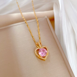 Detailed view of heart-shaped gold necklace with pink gemstone and pavé diamonds