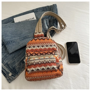 Close-up of ethnic style woven crossbody bag with orange geometric patterns and denim jacket