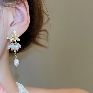 Detail of golden flower and pearl tassel earrings shown on a model side view
