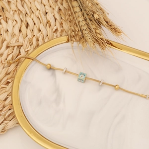 Detailed shot of golden evil eye bracelet with blue square charm and crystal spacers