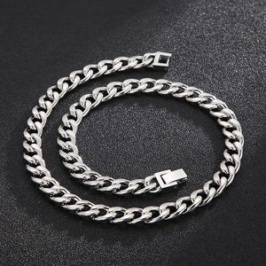 Detailed view of a silver titanium steel Cuban link chain on a black textured surface