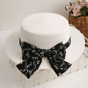 Detail view of woven straw hat with floral ribbon on a white metal basket