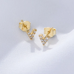 Detailed macro view of V-shaped gold S925 silver stud earrings with pave-set zircons