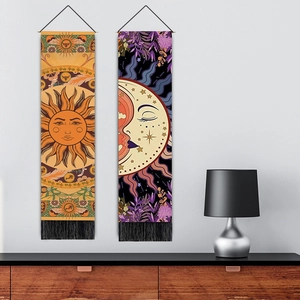Detail of bohemian sun and moon tapestries with black tassels hanging on a grey wall