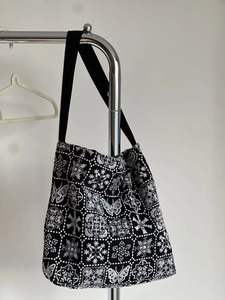 Close-up of intricate butterfly and floral embroidery on a black canvas tote bag