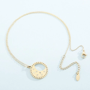 Dettaglio di una collana dorata con ciondolo a luna e stelle e pietre di zirconia
