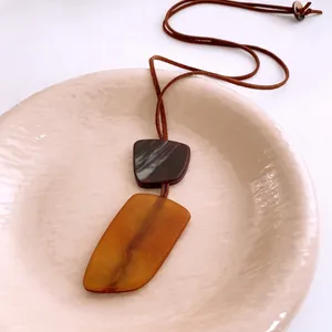 Ethnic resin geometric pendant necklace with brown leather cord in minimalist design