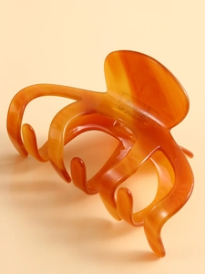 Detail of large orange acetate hair claw clip showing glossy finish and French branding