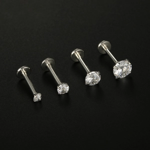 Macro view of four different sized silver titanium steel lip studs with sparkling zircons