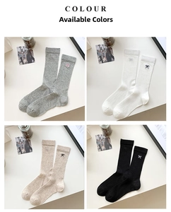 Close-up of four colors of knitted socks featuring elegant bow embroidery details