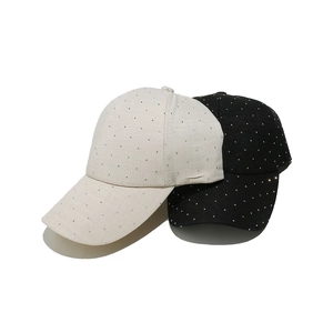 Détail de casquettes de baseball beige et noir avec strass brillants sur fond blanc