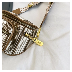 Close-up of geometric striped chest bag with gold hardware and wide shoulder strap
