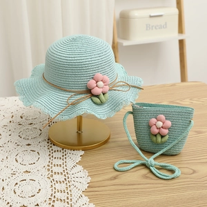 Close-up of mint blue straw hat and matching crossbody bag with pink fabric flower decor