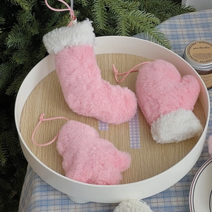 Détail de décorations de Noël en peluche rose avec chaussettes et gants sur plateau