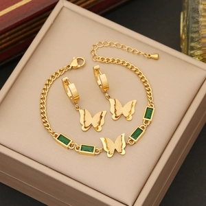 Golden butterfly jewelry set with emerald stones in a box, including earrings and bracelet