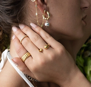 Detailed view of gold plated S925 sterling silver rings and chain earrings set on a model