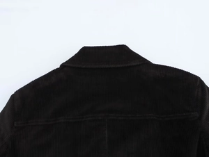 Gros plan détaillé sur la texture du velours côtelé noir au col arrière de la veste