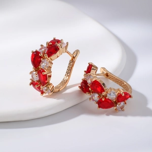 Boucles d'oreilles huggies en or rose avec zircons rouges et cristaux blancs sur céramique