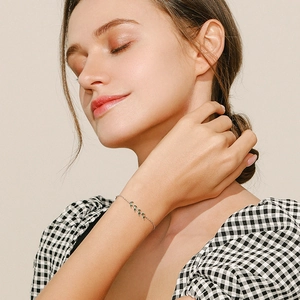 Minimalist S925 silver bracelet featuring green leaf-shaped gemstones on a female wrist
